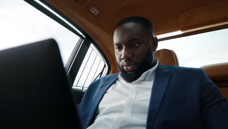 portrait african man working with laptop. african guy sitting at luxury car