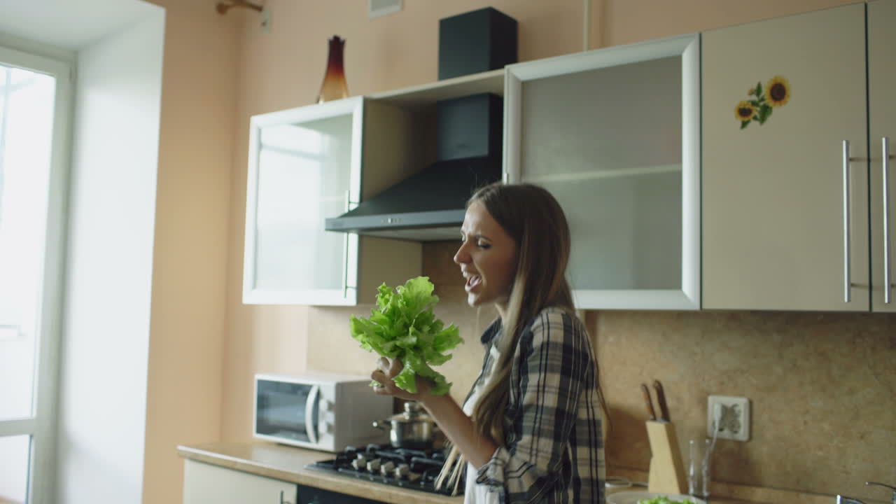 Donna che balla in cucina con un'insalata