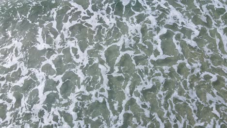 aerial view of clear waves breaking in oceanside