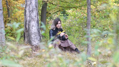 Brünettes-Mädchen-Im-Herbstwald-Hält-Ein-Gelbes-Blatt-In-Der-Hand-Und-Verbirgt-Ihr-Gesicht-Dahinter---Weitschuss