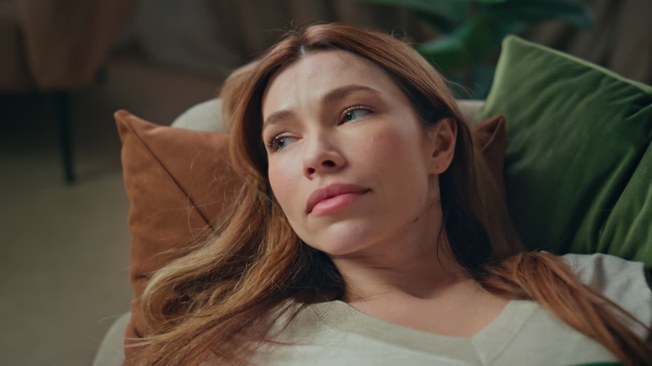 Unmotivated girl looking mobile phone screen lying couch close up. Sleepy woman