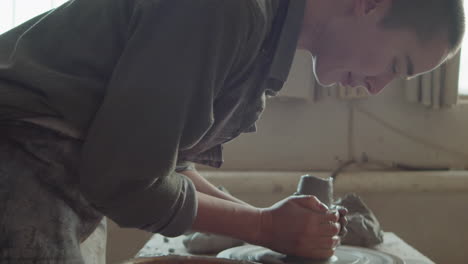 woman learning wheel throwing with senior potter