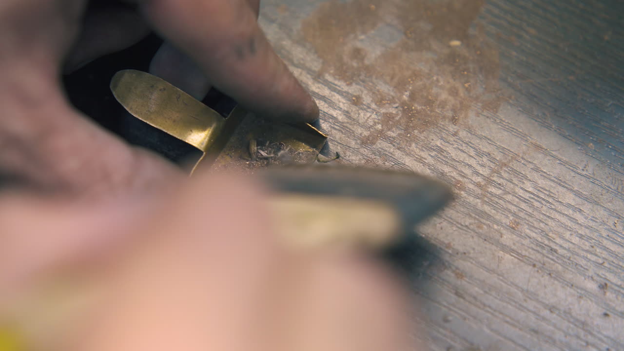 jeweler brushes gold sawdust into small shovel close view