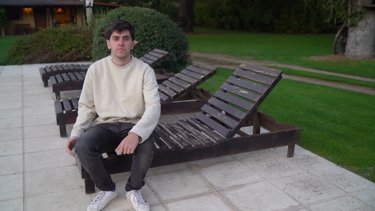 백인 남자가 야외에 있는 의자에 앉아 있다.