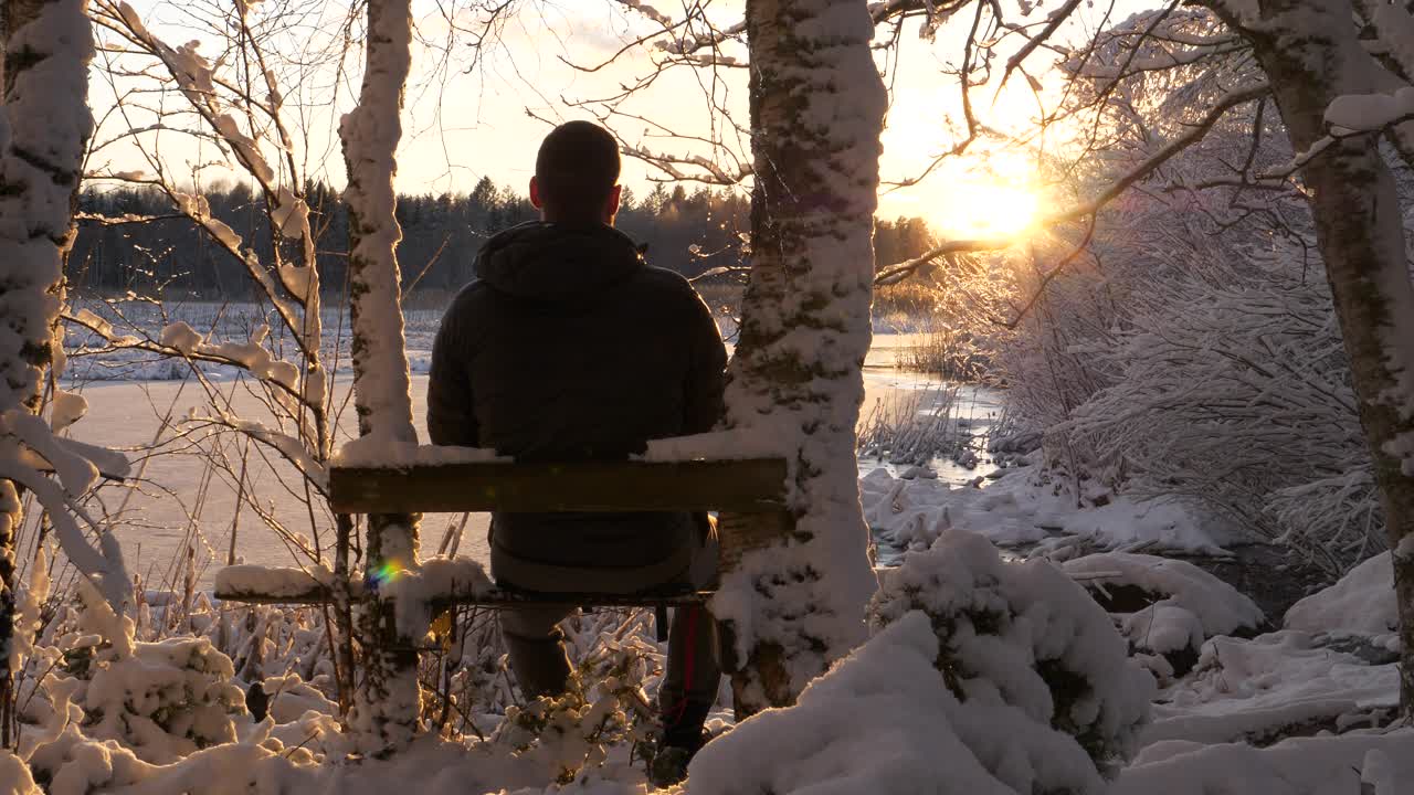 Man enjoying winter wonderland view, frosty trees at golden sunset