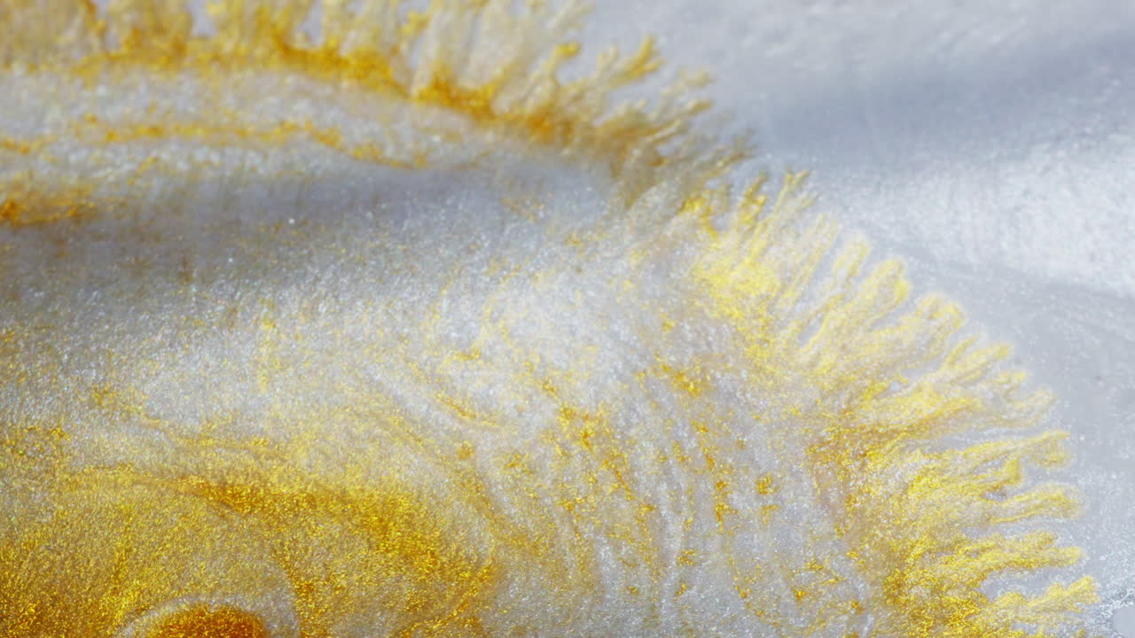Yellow shiny ink flowing across a liquid surface. Macro view