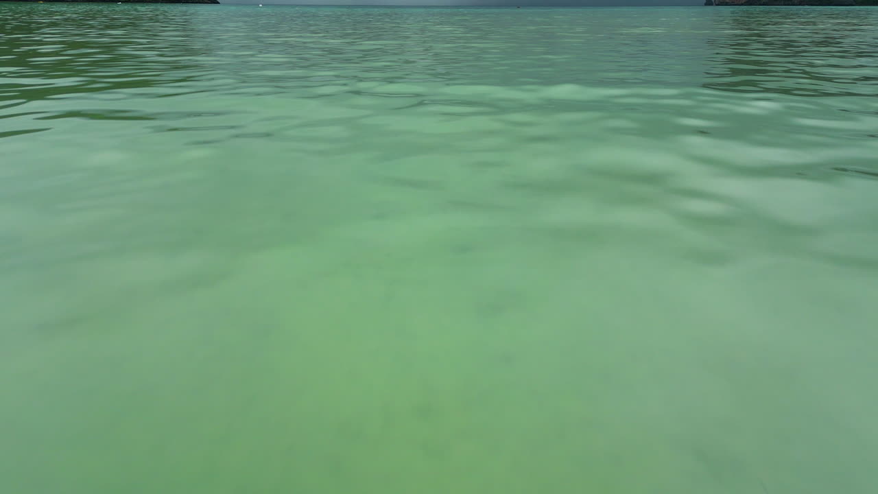 navegando en un barco tradicional de cola larga en la superficie del agua turquesa en la isla de kho phi phi, una enorme nube de lluvia en el fondo, tailandia, pov shot