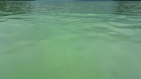 navegando en un barco tradicional de cola larga en la superficie del agua turquesa en la isla de kho phi phi, una enorme nube de lluvia en el fondo, tailandia, pov shot