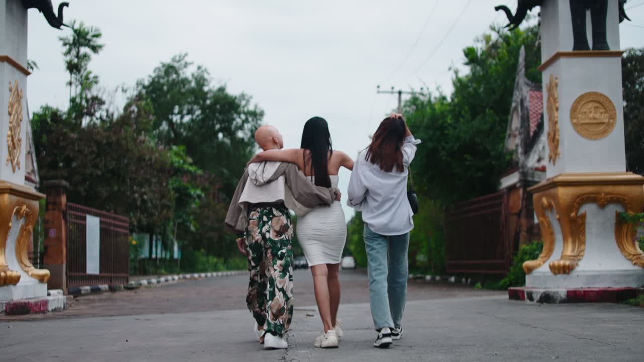 Three women walking through a gate with elephant statues