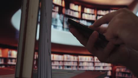 a person holds a smartphone in front of a large library — symbolizing the digital shift from traditional knowledge to ai-driven information access