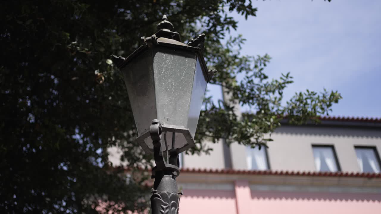 An old street lamp against a backdrop of trees and a building