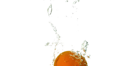 naranja sumergiéndose en el agua sobre un fondo blanco