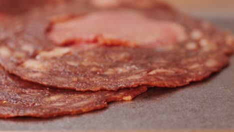 black bull sausage ham, tongue pork dry-cured sausage on a black background, traditional spanish delicatessen food, close up.