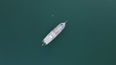 cinematic top view of the traditional arabian fishing boat moored on the surface of gulf sea in sharjah, uae, seascape with boat view from above. 4k uhd