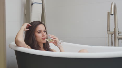 Mujer-Acostada-Y-Relajándose-En-El-Baño-En-Casa-Bebiendo-Una-Copa-De-Vino