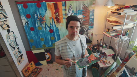 portrait of artist with palette and brush in creative studio