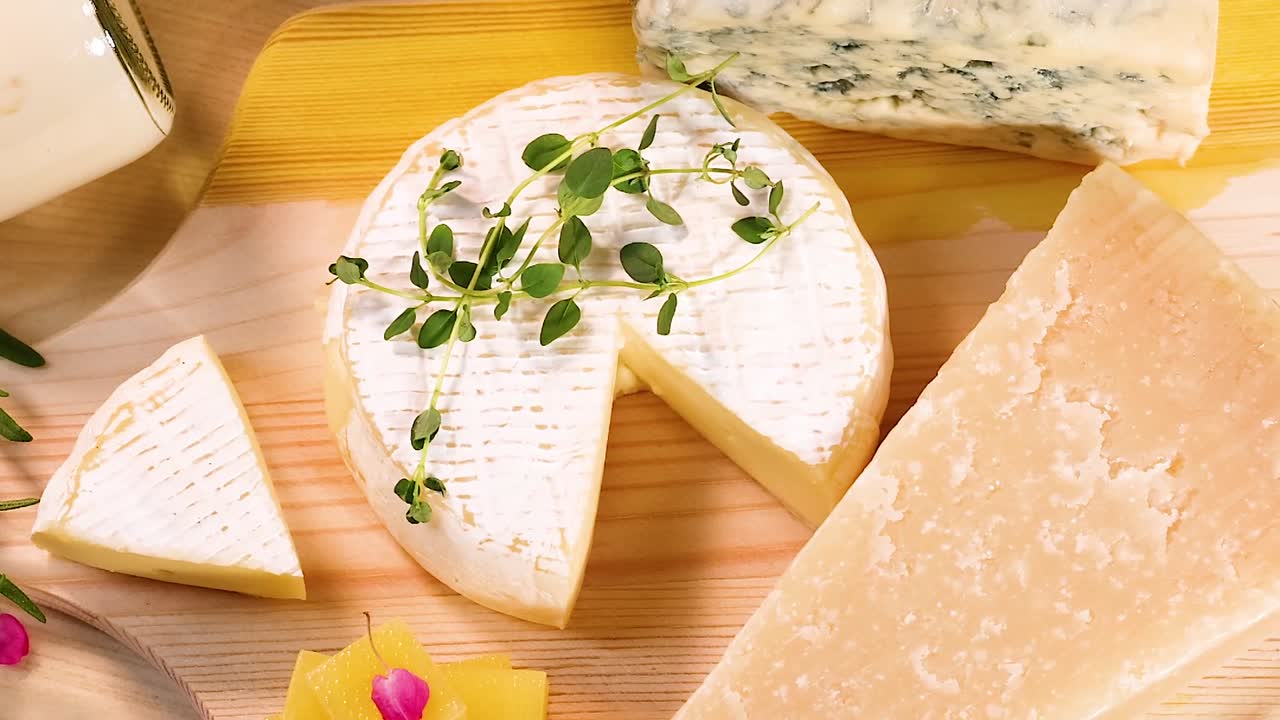 Primo piano ad angolo acuto che mostra diversi spicchi di formaggio, blocchi e vasetti di yogurt sul legno