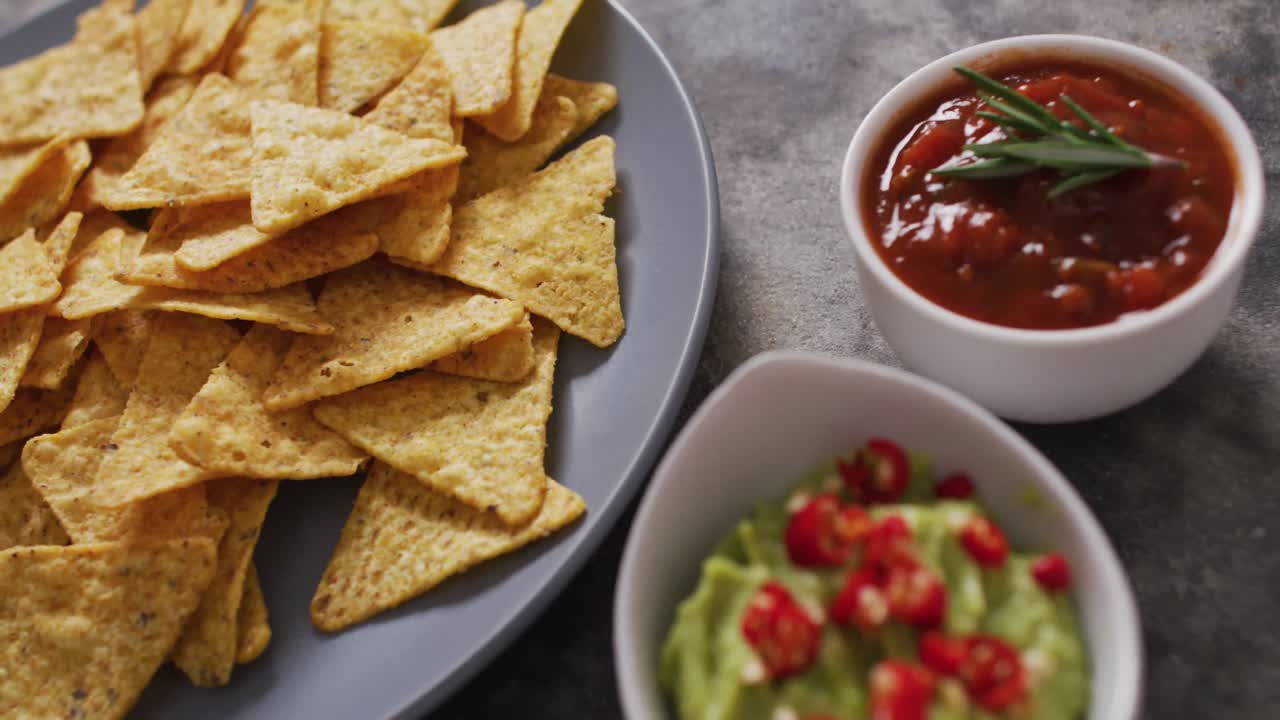 cerca de nachos en un plato y salsas en superficie negra