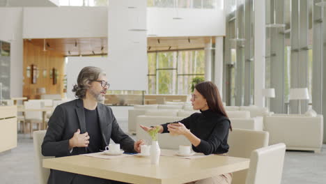 business-like couple discussing work at restaurant