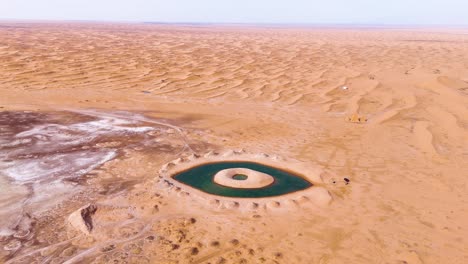 Zoom-away-aerial-shot-of-the-Artificial-Eye-Lake-in-the-Tengger-Desert,-Inner-Mongolia-Autonomous-Region,-China