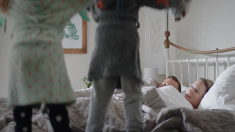 niños felices saltando en la cama despertando madre y padre disfrutando de una mañana lúdica con los niños