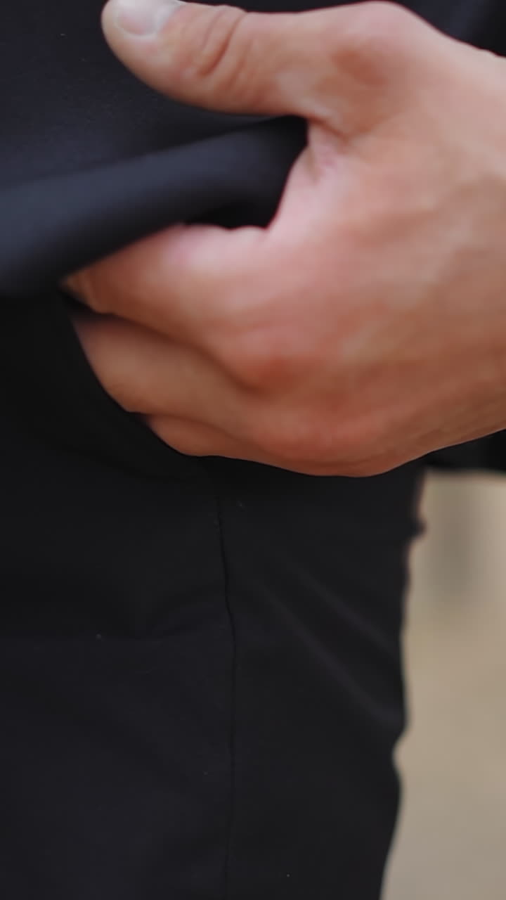 Gentleman in black office suit puts hand into pocket standing by pine tree in park closeup slow motion. Stylish businessman rests after work in nature