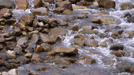 Clear-stream-running-through-stone-boulders-Abundant-river-flowing-in-slow-motion