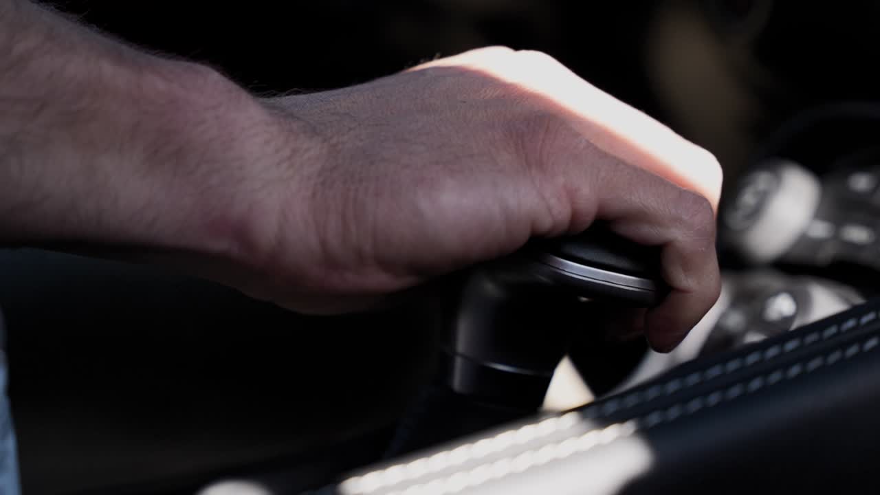Immagine concettuale di una persona che afferra una leva del cambio di un'auto, a rappresentare i cambiamenti di carriera e il progredire.