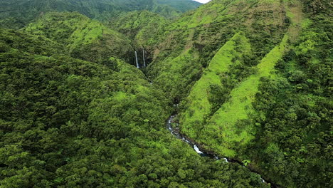 Aerial-View-of-Waterfall-in-Rolling-Hills-and-Green-Landscape-in-Kauai-Hawaii