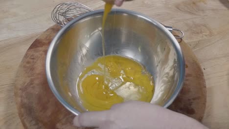 close slow motion shot of cracking eggs into a bowl and whisking