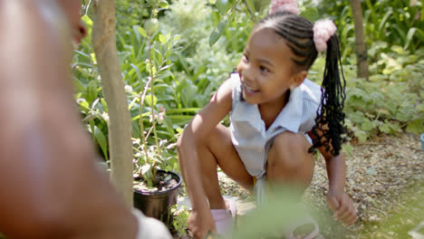 Happy-african-american-granddaughter-with-grandmother-working-in-garden,-in-slow-motion