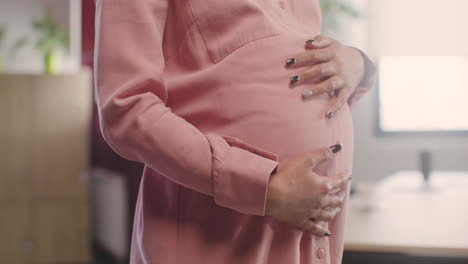 nahaufnahme der hände der schwangeren frau, die ihren bauch streicheln