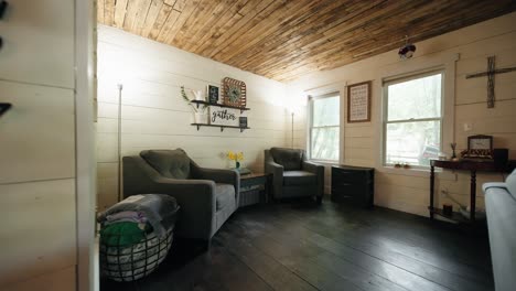 Push-in-shot-of-a-nook-in-the-living-room-of-a-farmhouse-with-2-chairs-and-a-sign-that-says-"Gather