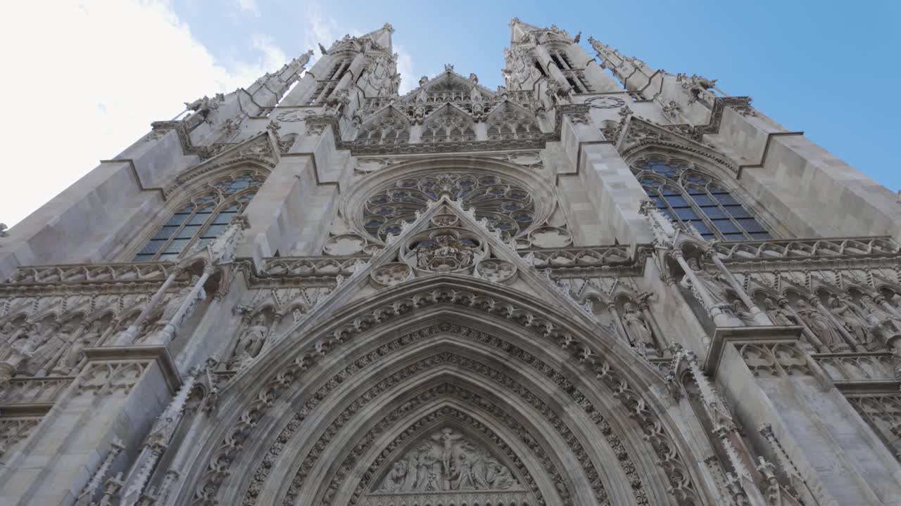 Ornate stone facade and large wooden doors of Votive Church in Vienna, Austria