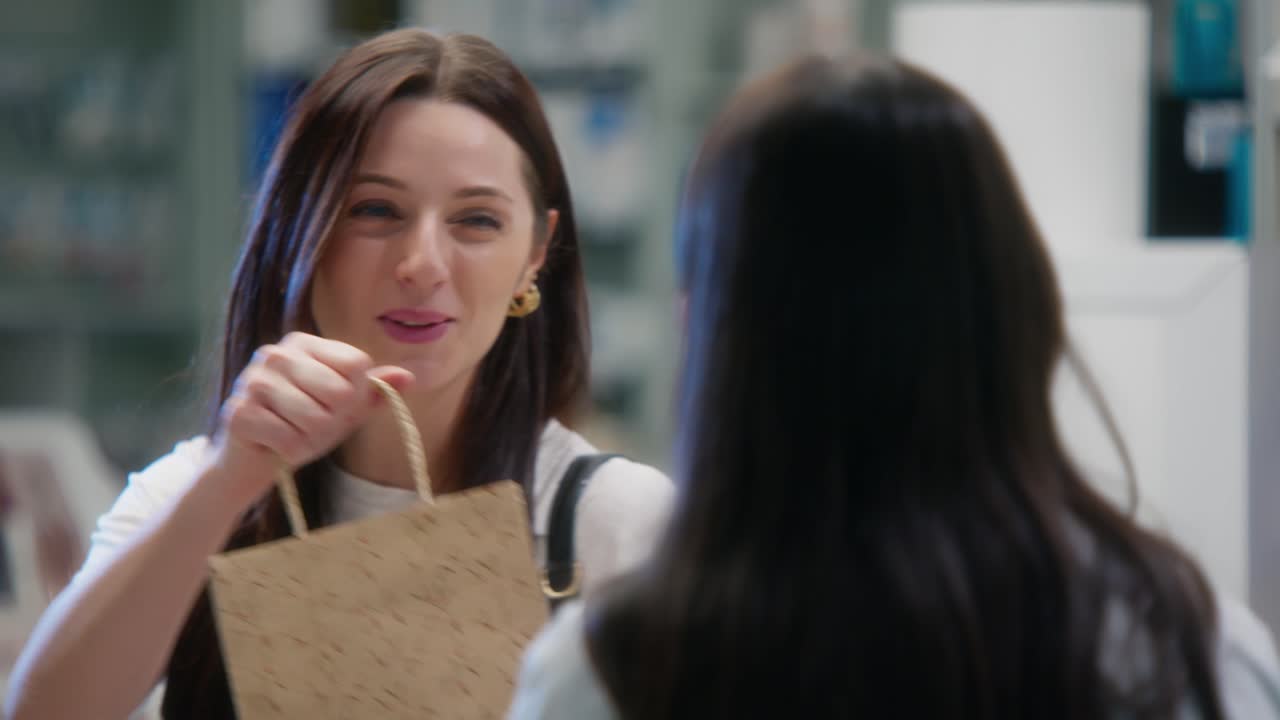 Smiling woman takes a paper bag from pharmacist before leaving the pharmacy, shot from counter perspective