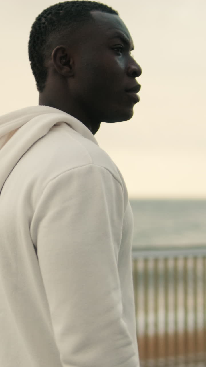 Young Black Man in Hoodie Turns Head to Look at Ocean