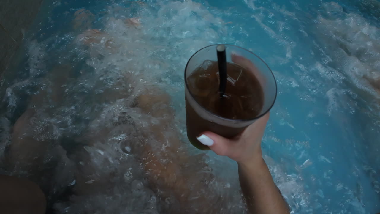 pareja relajándose en el spa jacuzzi con bebida de cola oscura en la mano centro de relajación