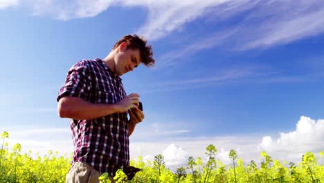 Man-taking-picture-from-camera-in-mustard-field