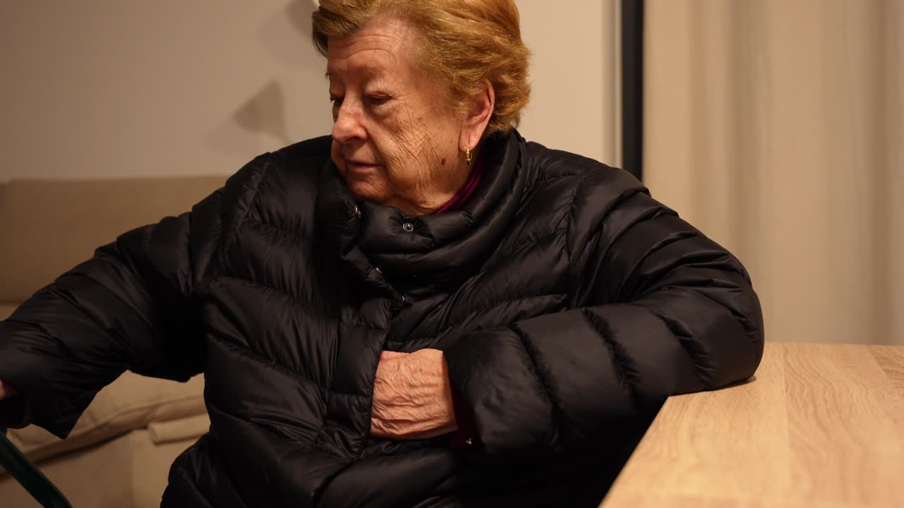 Cute wrinkled and cold grandma wearing a coat at home