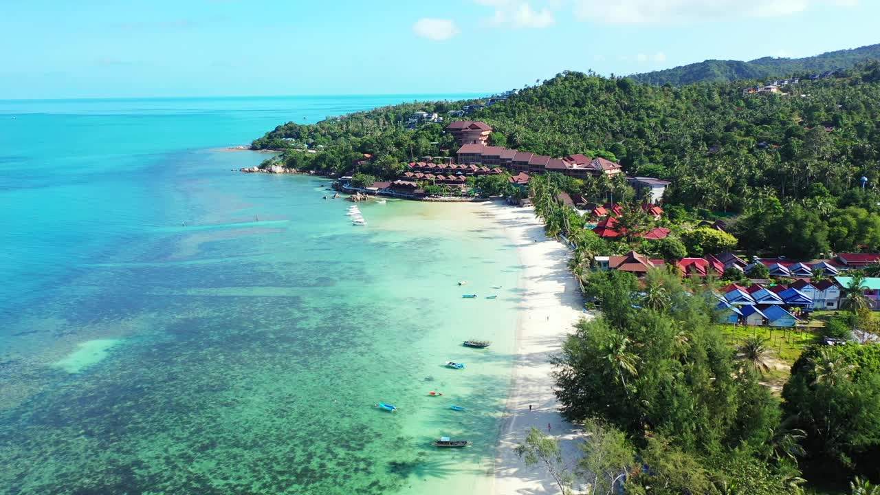 Vacations resort on green slope of hill on seaside of tropical island with white sandy beach washed by turquoise lagoon in Thailand