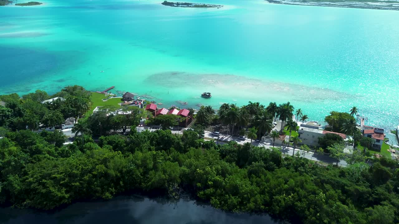 Drone aerial landscape of Bacalar town village with hotel resorts and Cenote Azule lagoon lake surrounded by nature trees island sandbar Mexico travel tourism