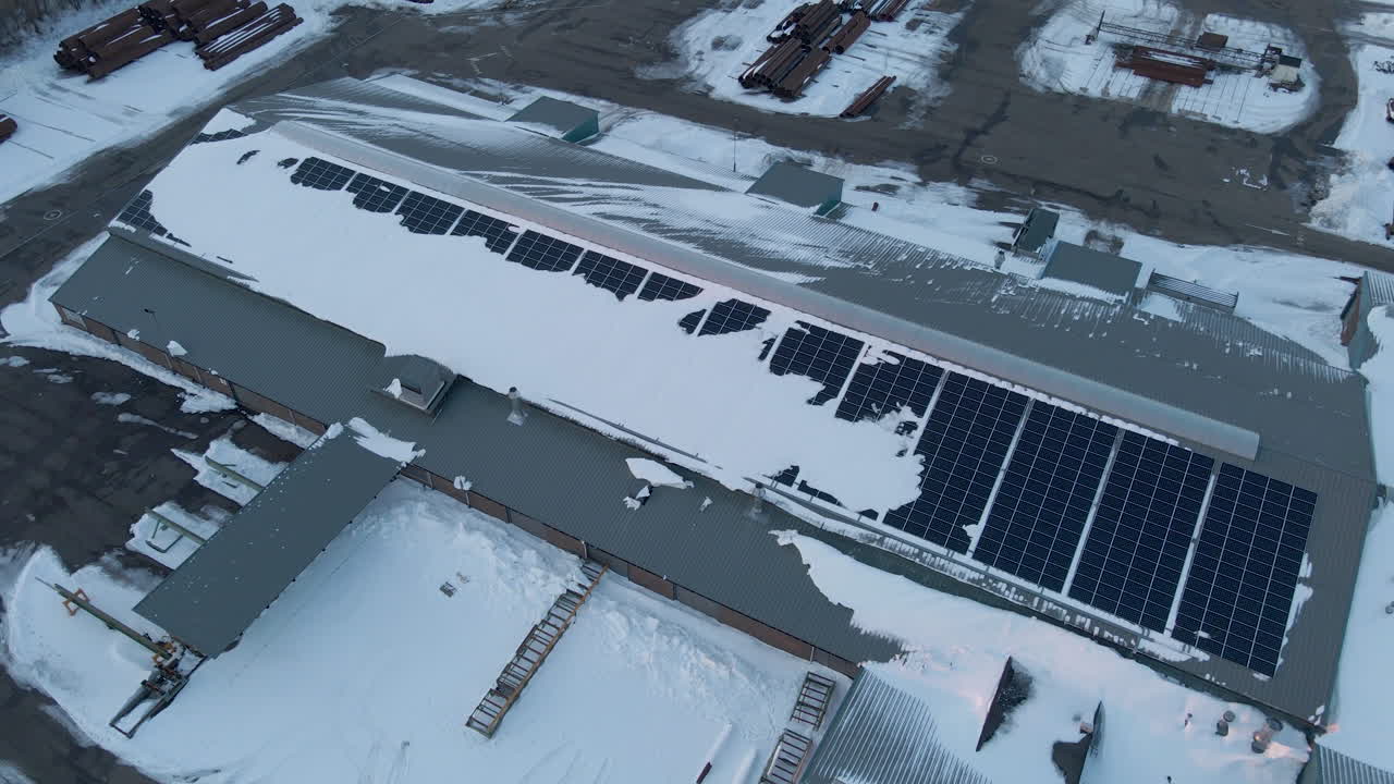 창고 옥상에 있는 눈 덮힌 태양 전지판의 지브 다운