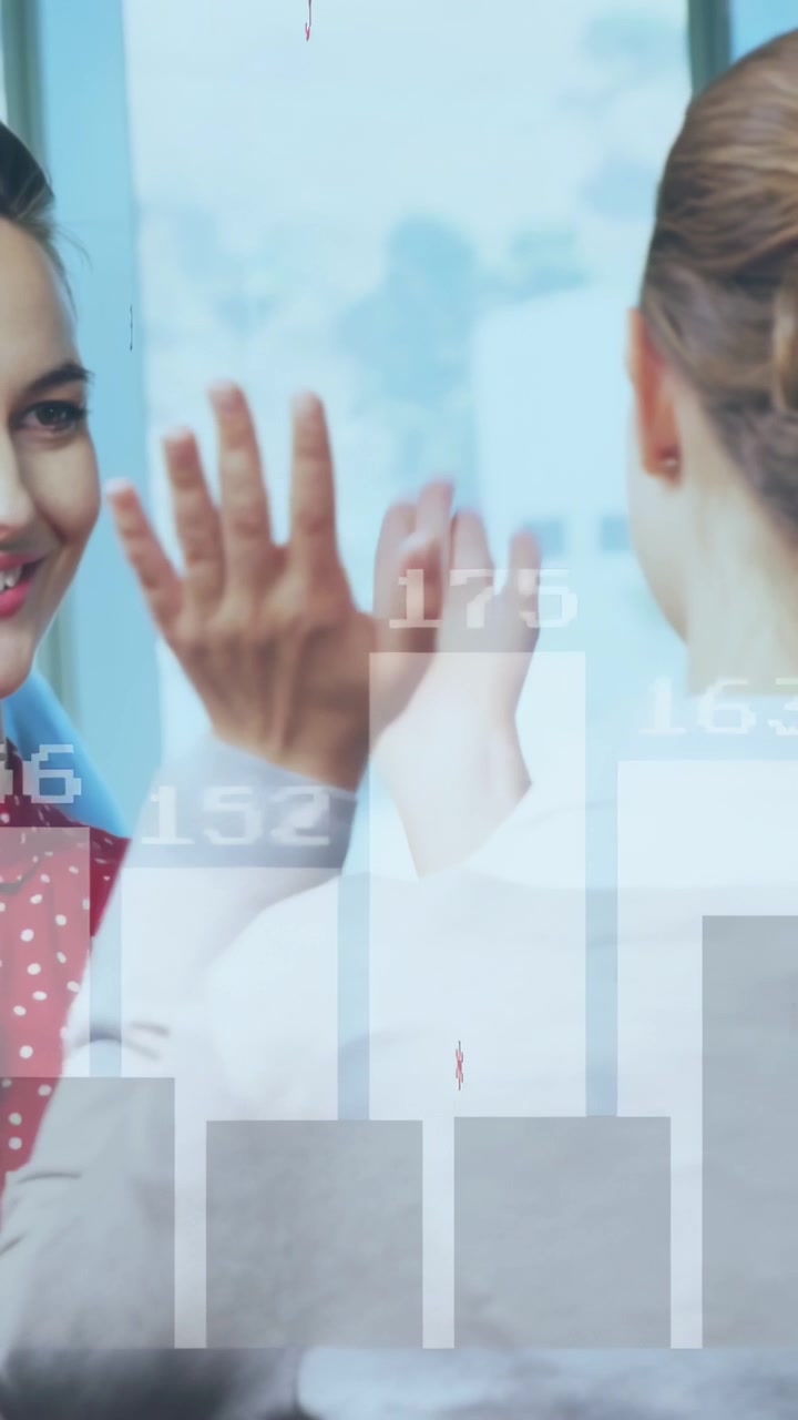 Video vertical: Dos mujeres chocando las cinco en un entorno de negocios, después de una superposición de gráficos mostrando métricas en aumento.