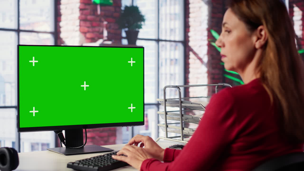 Woman working on computer with green screen