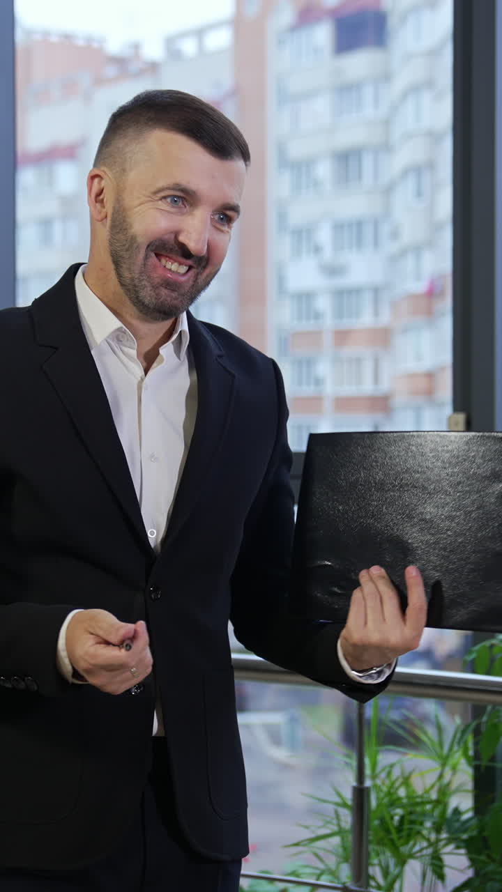 Businessman wearing suit talking to business colleagues or partners sitting at conference table. Male leader holding a folder in his hands showing a chart to his colleagues. Vertical video