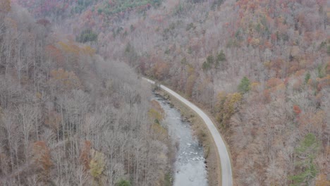 Drone-shot-of-river-and-road-from-high-altitude-flying-downstream-in-late-fall-in-western-North-Carolina