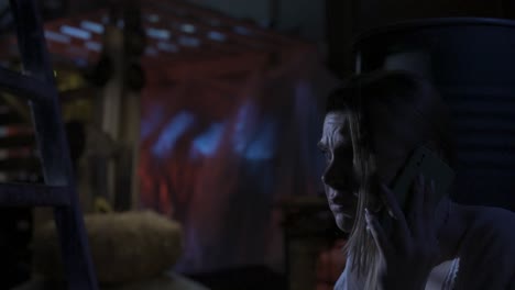 scared blonde girl victim of the horror maniac hiding from the man behind the barrel in the - horror movie scene. closeup shot, focus on female face. scared blonde girl model, victim of the horror maniac hiding from the man behind the barrel in the old warehouse. she looks around, very scared