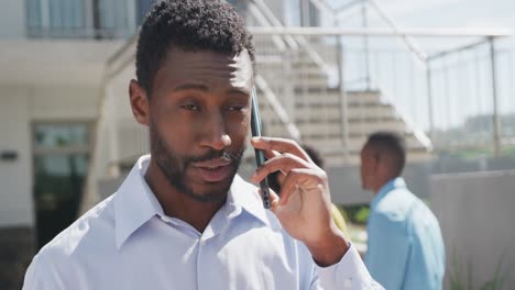 happy african american businessman talking on smartphone at office, slow motion