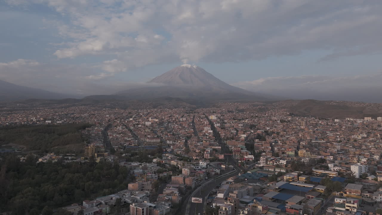 Forwards moving drone shot above Arequipa Peru with view on the mountain near sunset time with clouds in the sky LOG