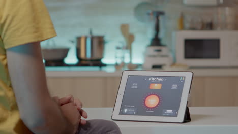 hombre mirando una tableta con software inteligente colocado en la mesa de la cocina